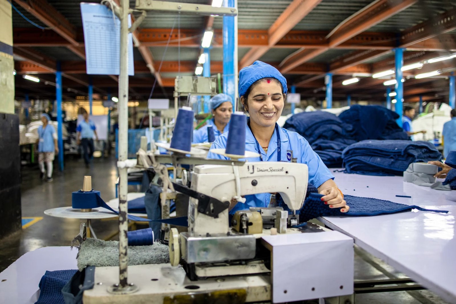 Team member finishing blue institutional fabric on an industrial machine